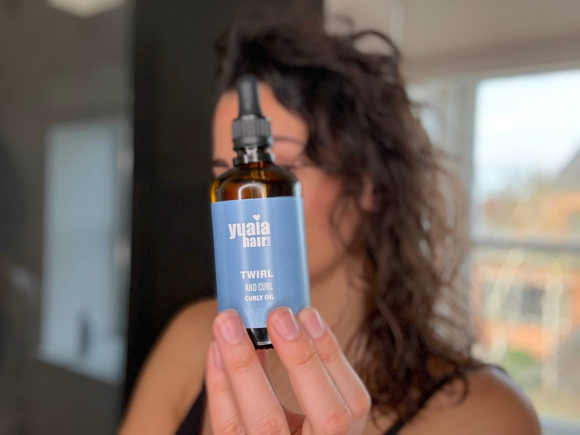Kvinde der står med Yuaia Haircare Twirl and Curl Curly Oil