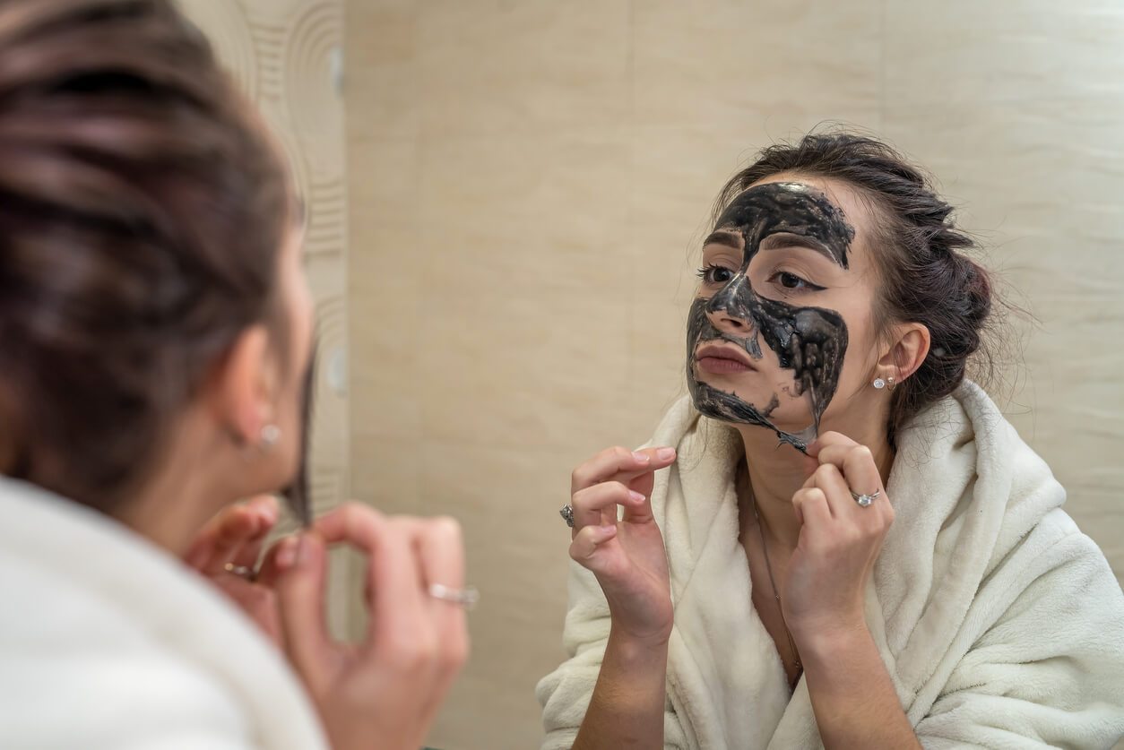 Kvinde fjerner black mask fra ansigtet foran spejl