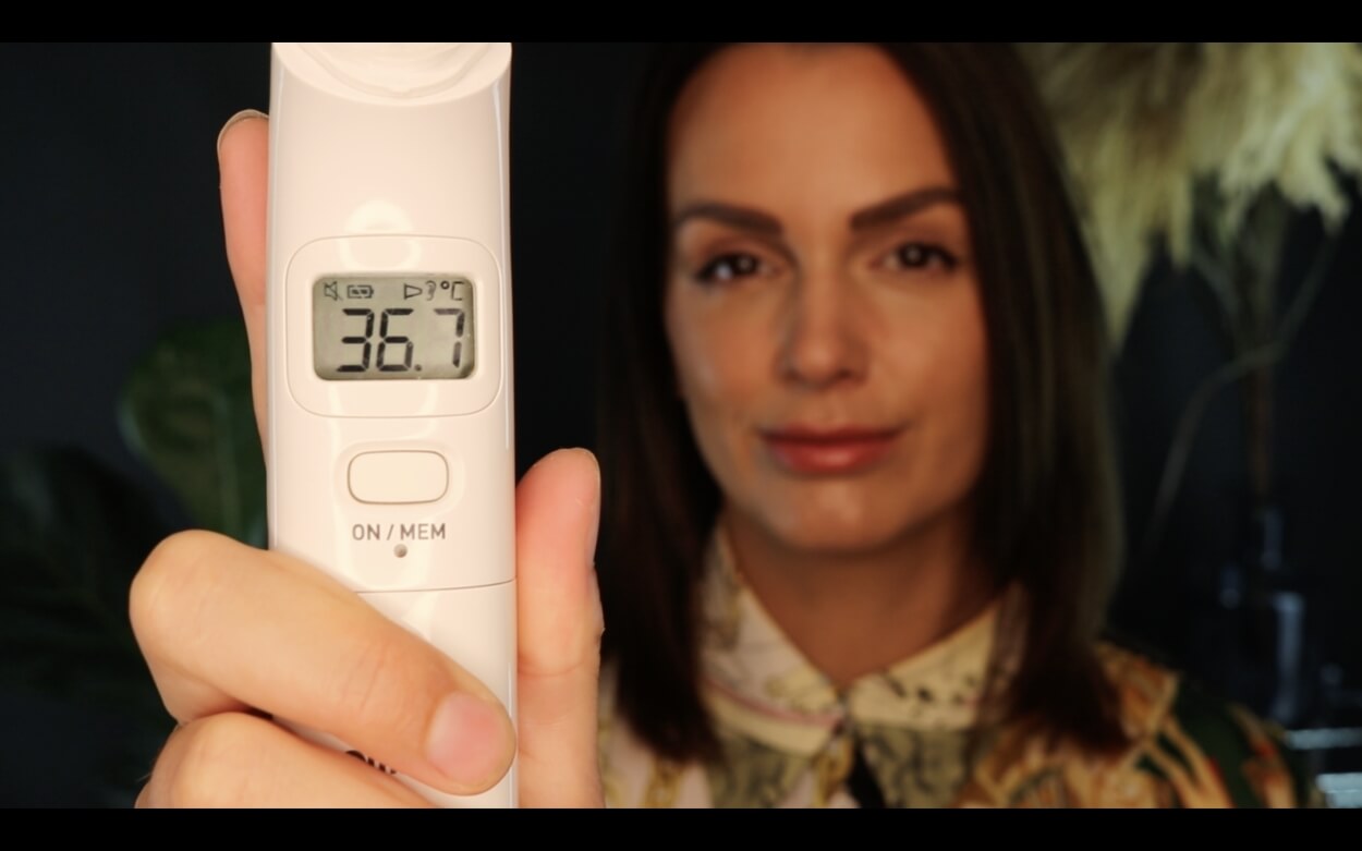 Kvinde fremviser øretermometer med temperaturmåling