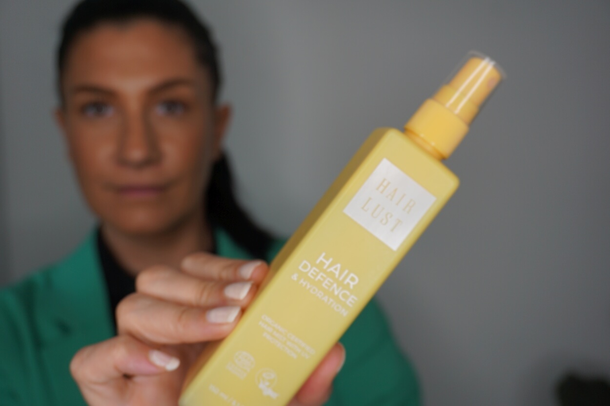Kvinde holder Hairlust solspray til håret i hånden