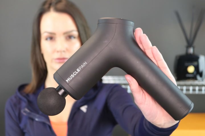 Kvinde holder Musclepain massagepistol foran sig