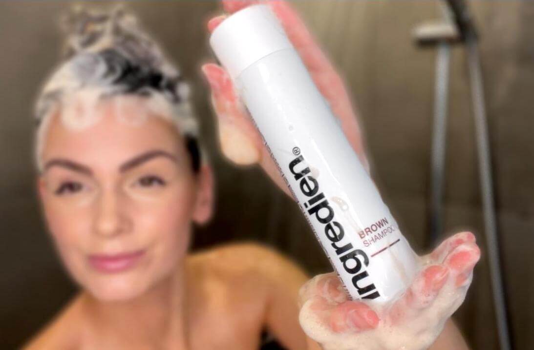 Kvinde i bad der holder Brown shampoo fra ingredien