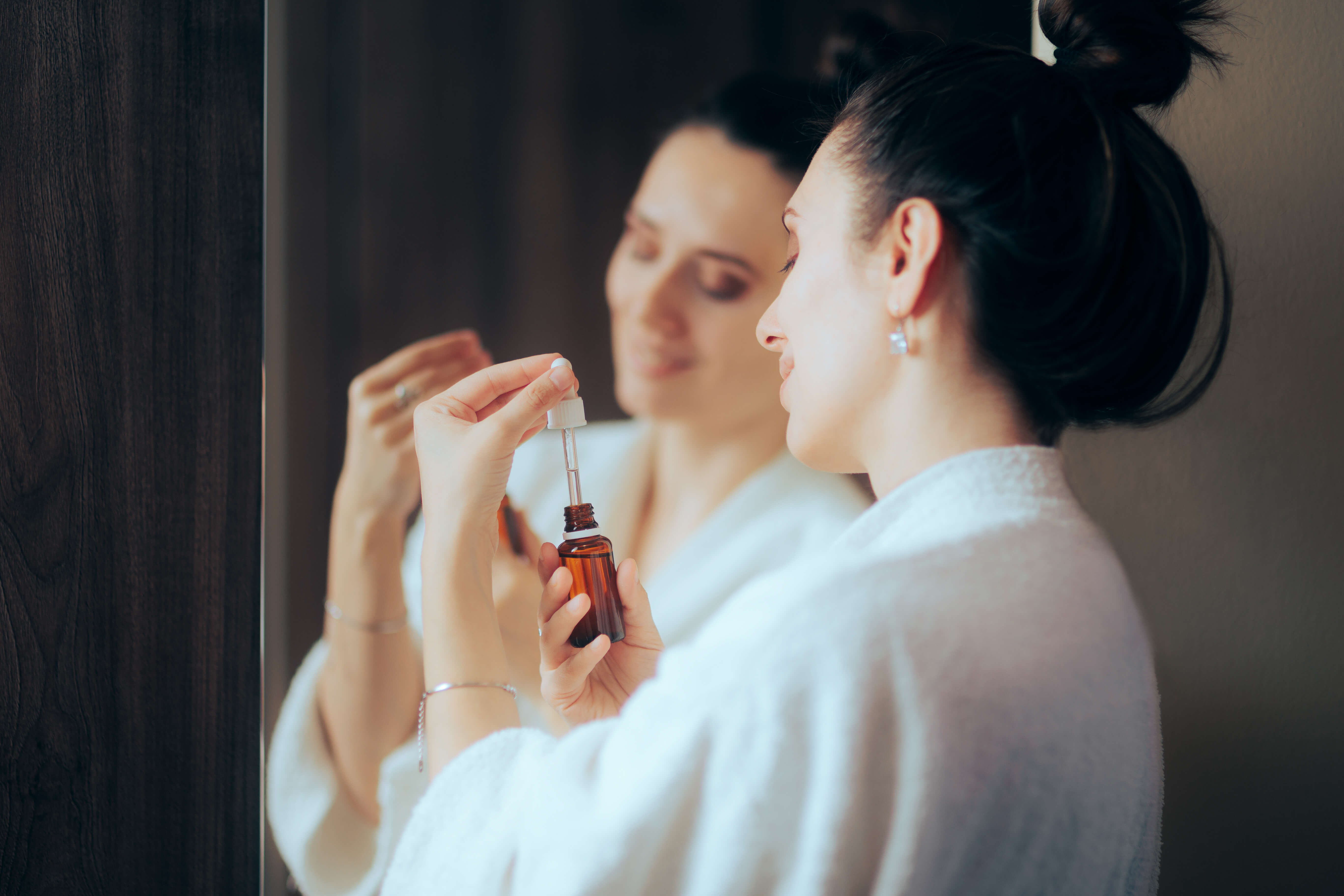 Kvinde i morgenkåbe med retinol serum i hånden