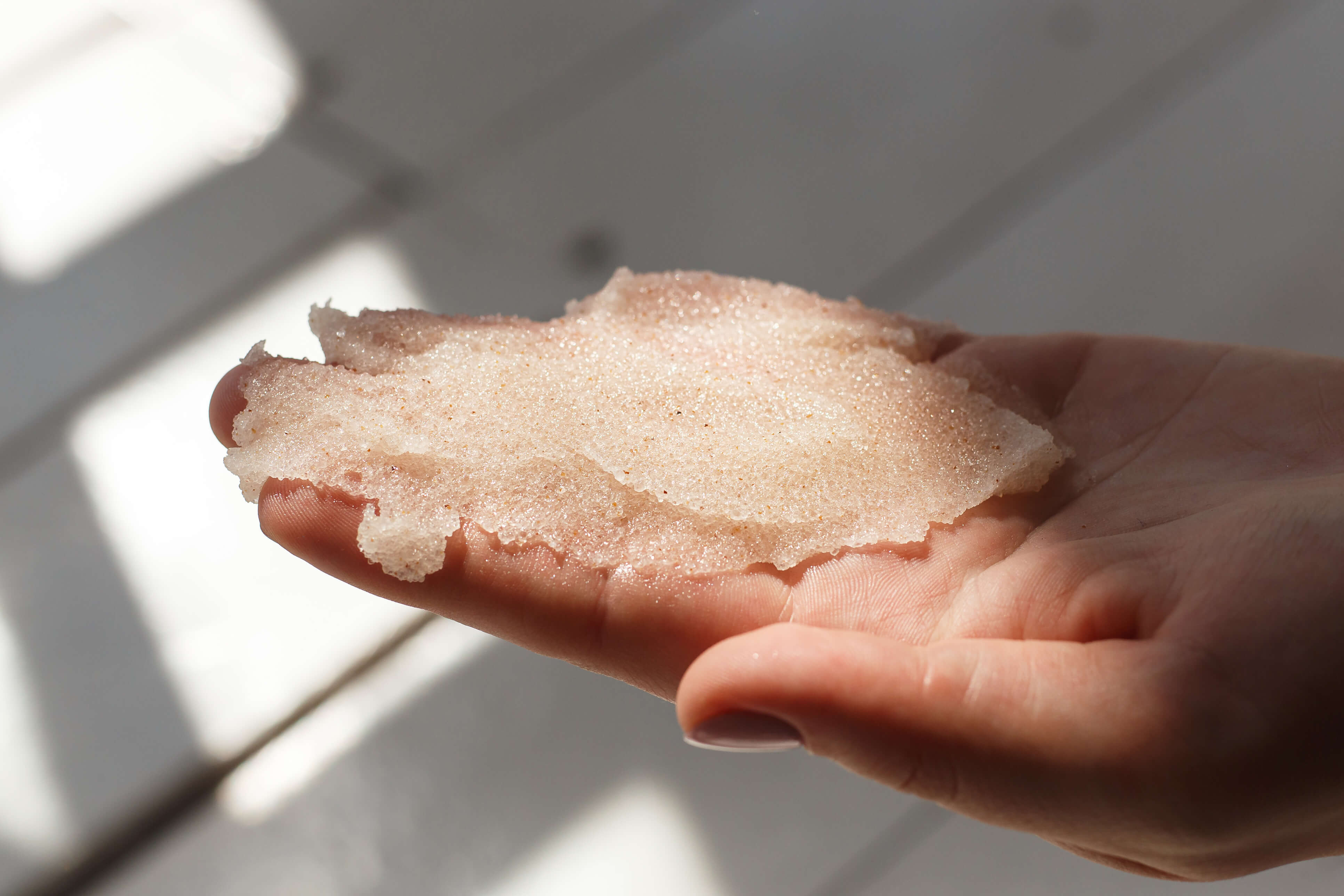 Kvinde med bodyscrub i hånden til at fjerne selvbruner
