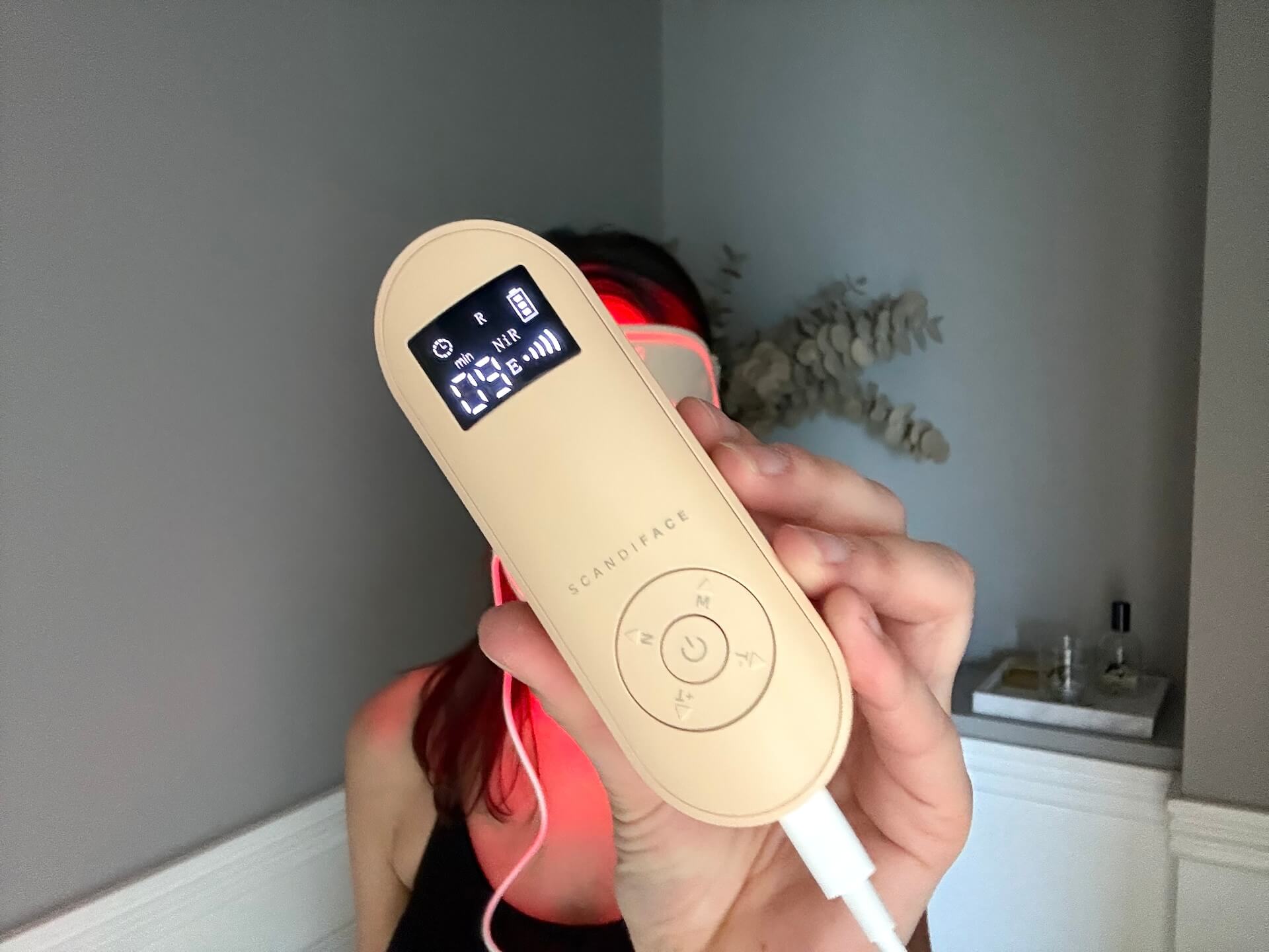 Kvinde med fjernbetjening til Scandiface Skinboosting LED mask