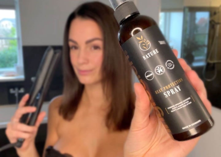 Kvinde med glattejern og ingredien Nature Heat Protection Spray i hånden