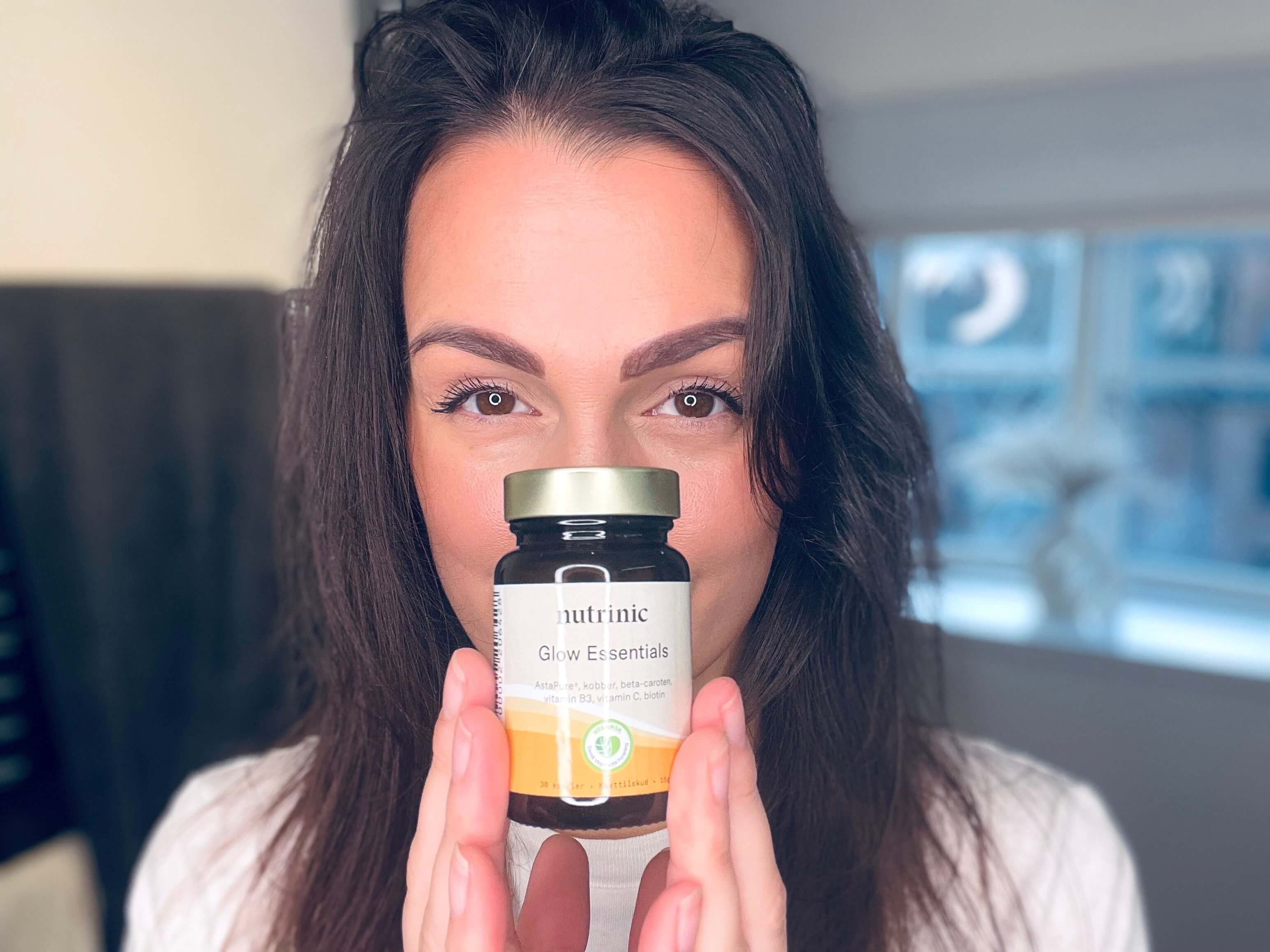 Kvinde med Glow Essentials fra Nutrinic i hånden