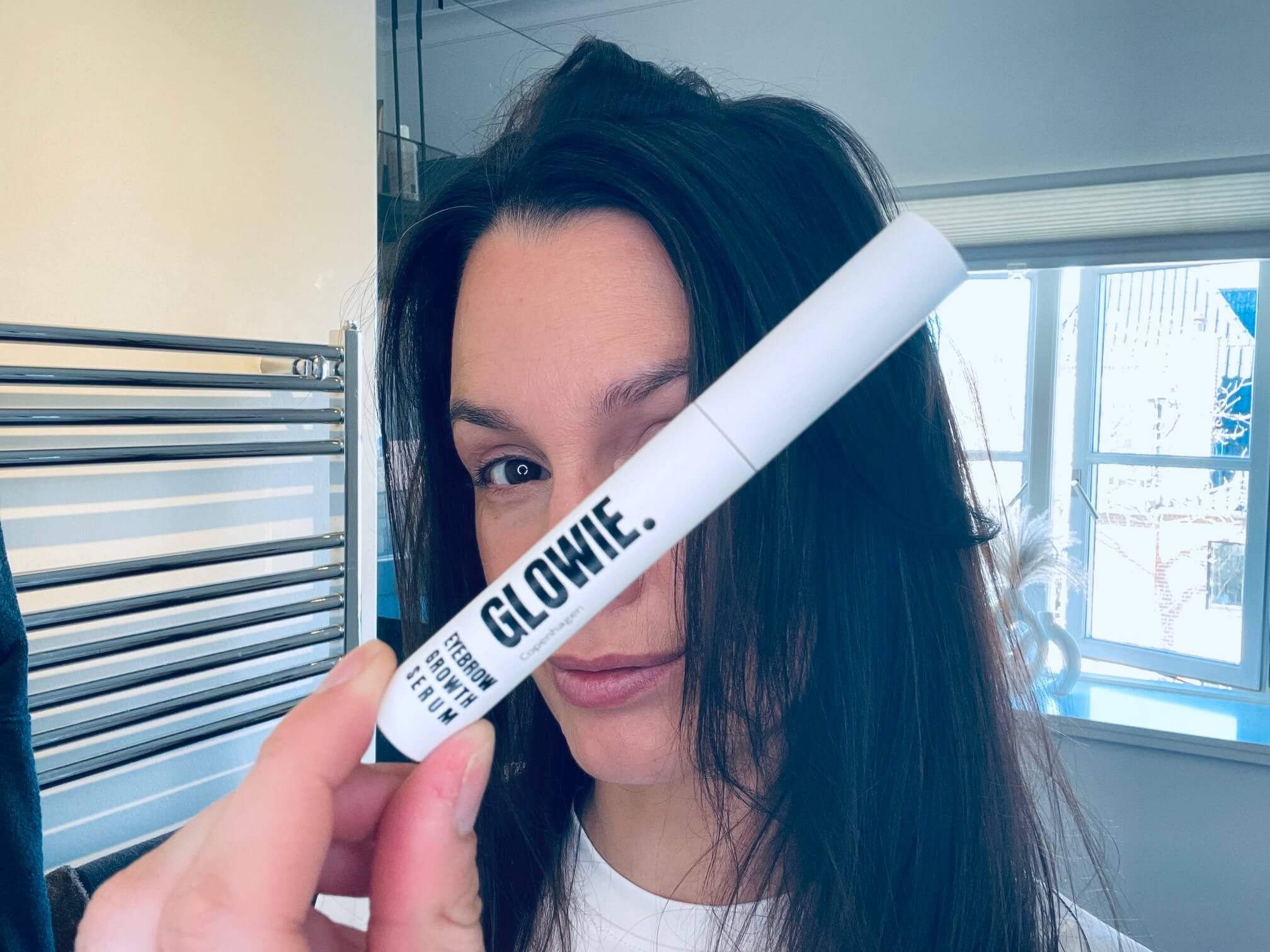 Kvinde med Glowie Eyebrow Growth Serum foran sig