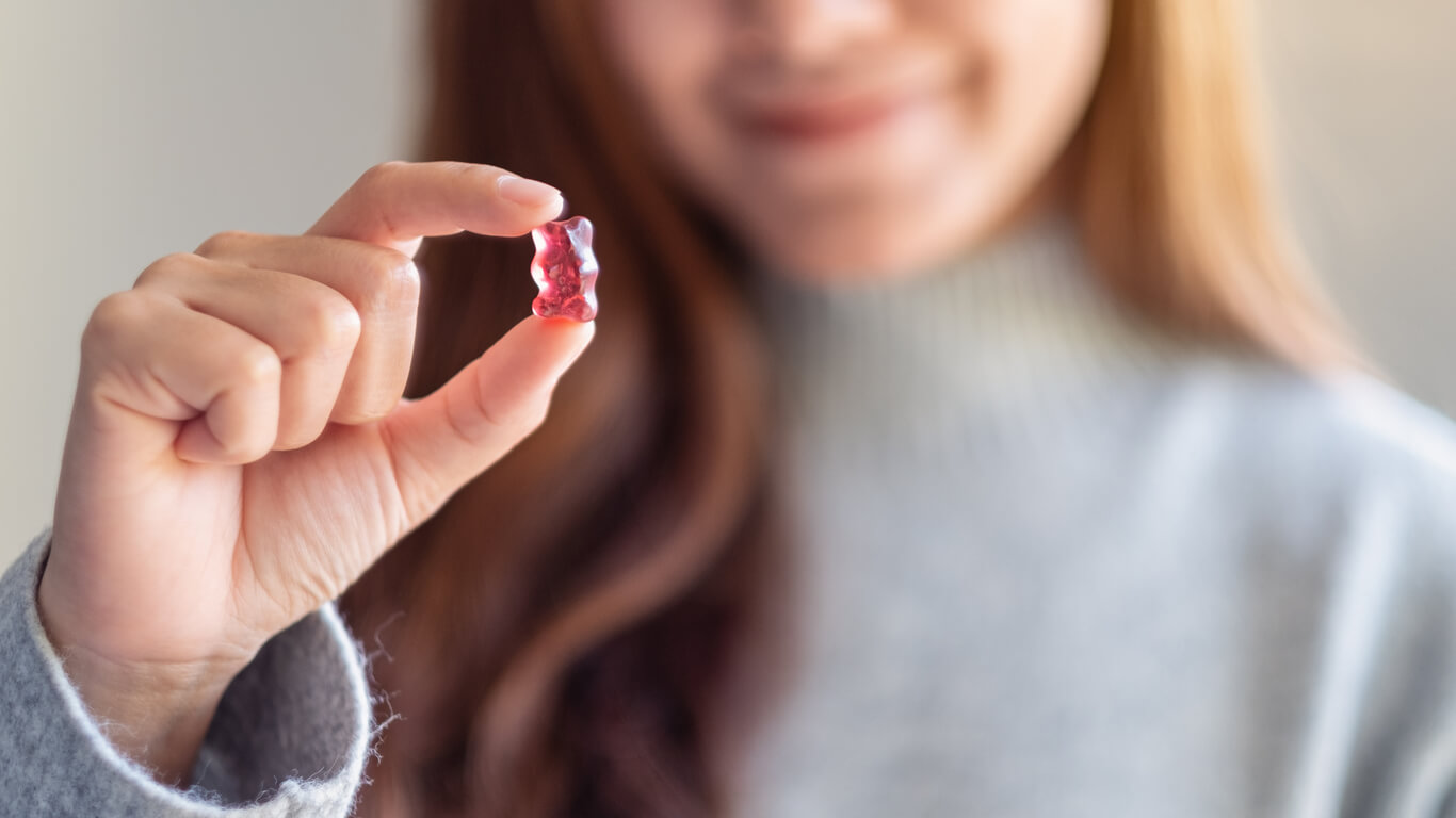 Kvinde med kraftigt hår med hårvitamin vingummibamse i hånden