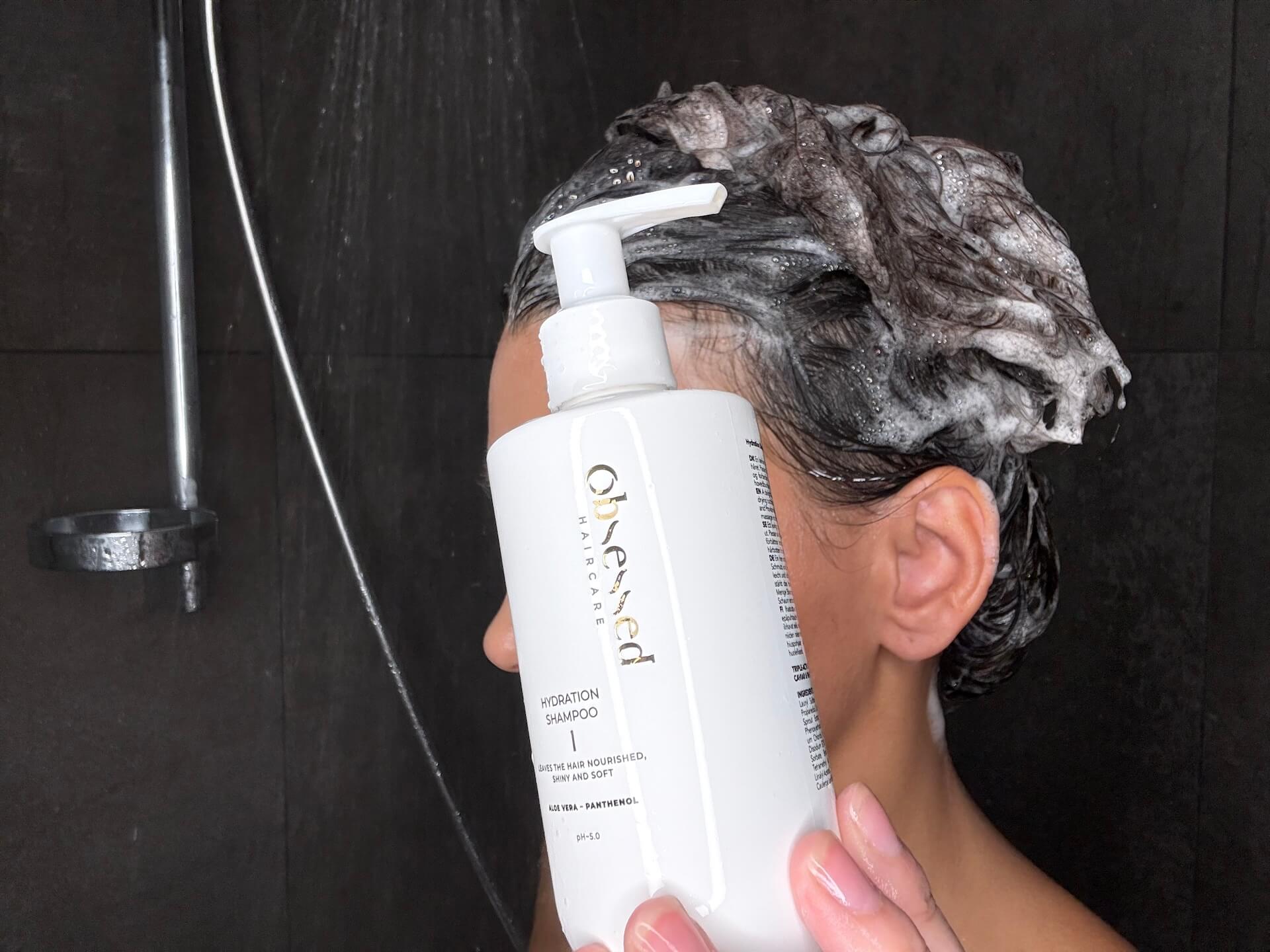 Kvinde med Obsessed Haircare Hydration Shampoo i håret