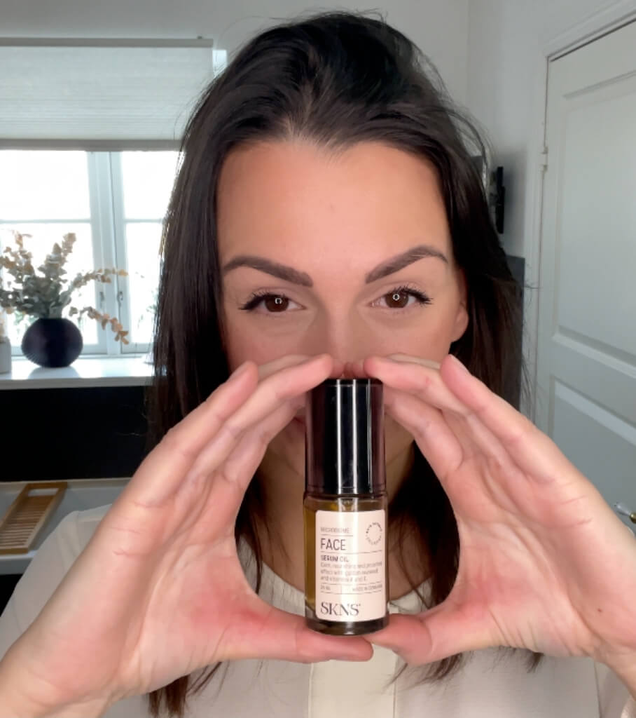 Kvinde med SKNS Face Serum Oil i mellem to hænder