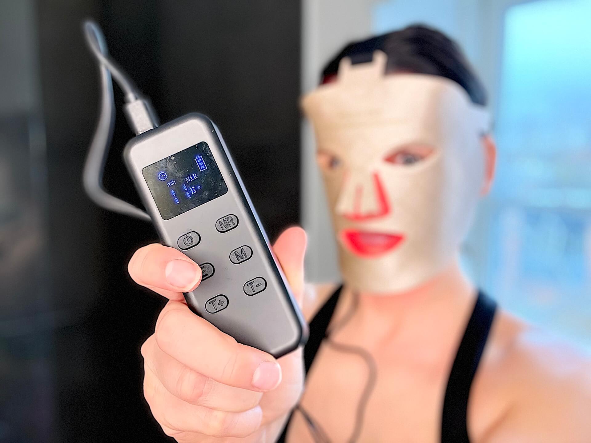 Kvinde med SweHealth Infrarød LED ansigtsmaske der viser fjernbebetjening