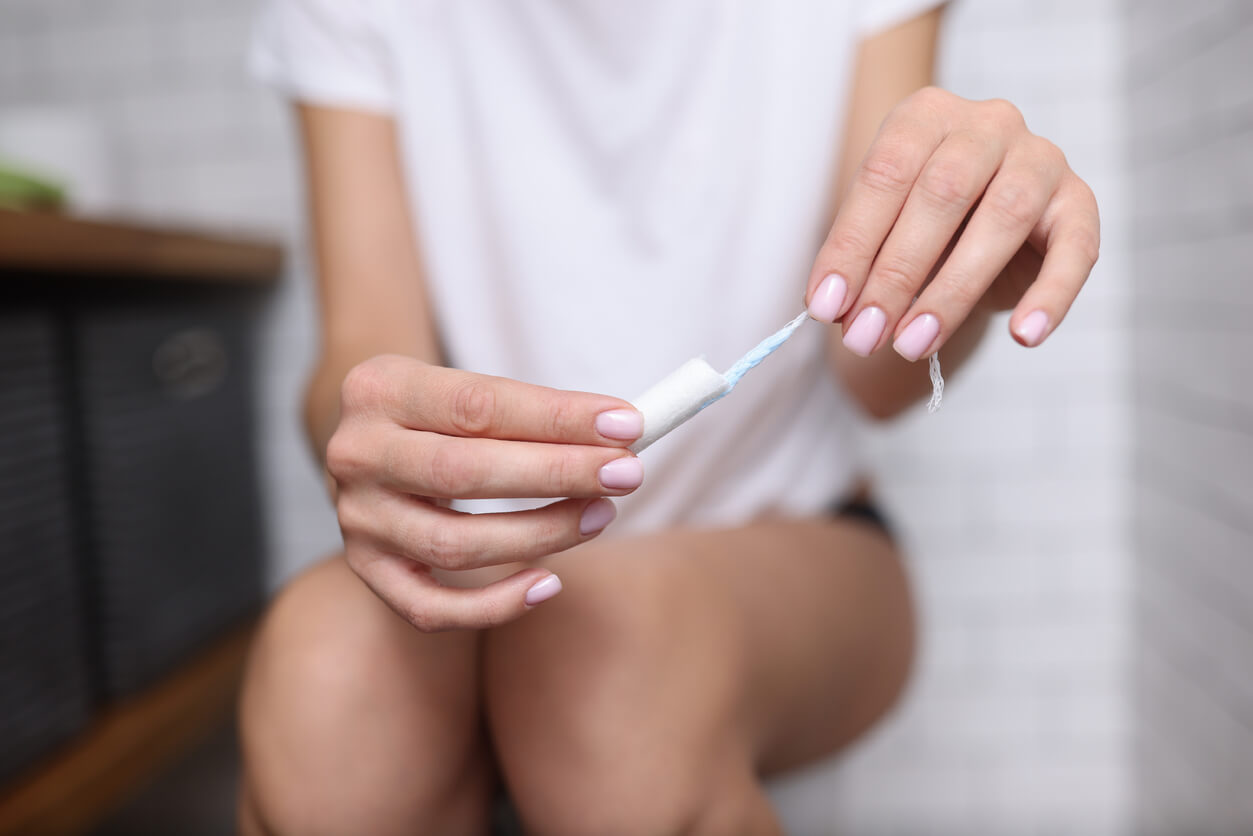 Kvinde på topilet skifter tampon