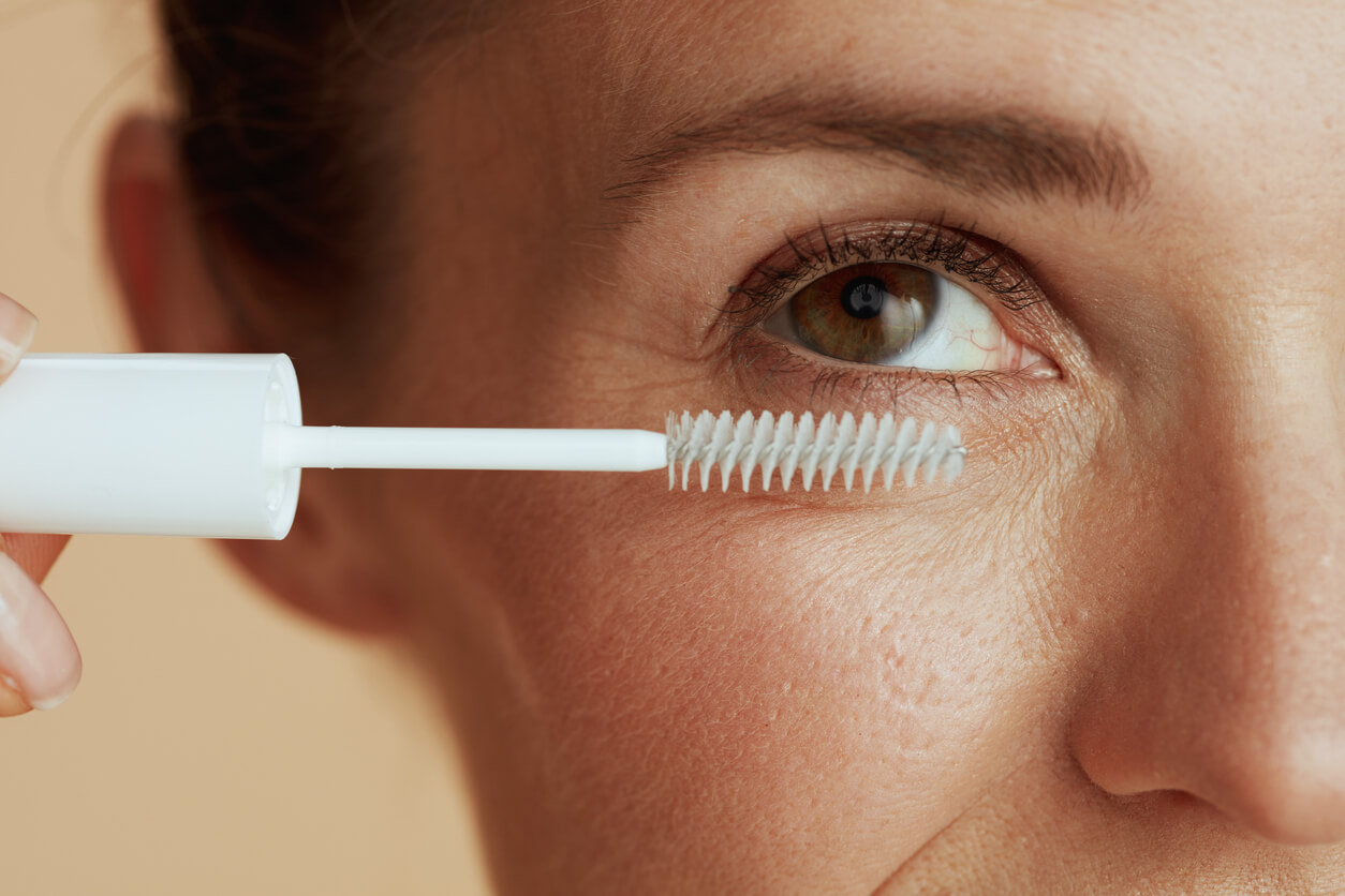 Kvinde påfører lash gel transparent mascara på øjenvipper og øjenbryn