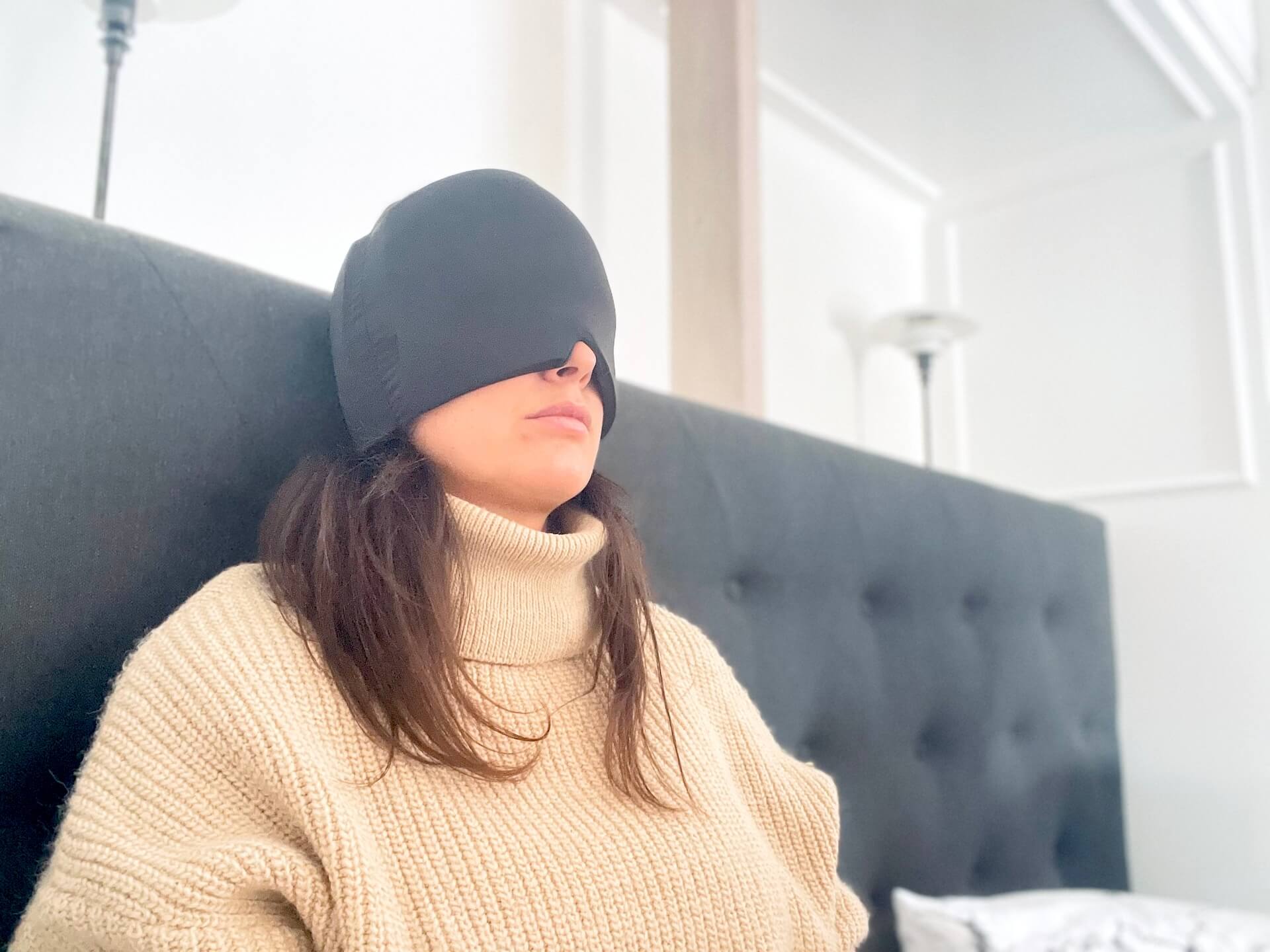 Kvinde sidder i seng med HealHeal Pro migrænemaske på