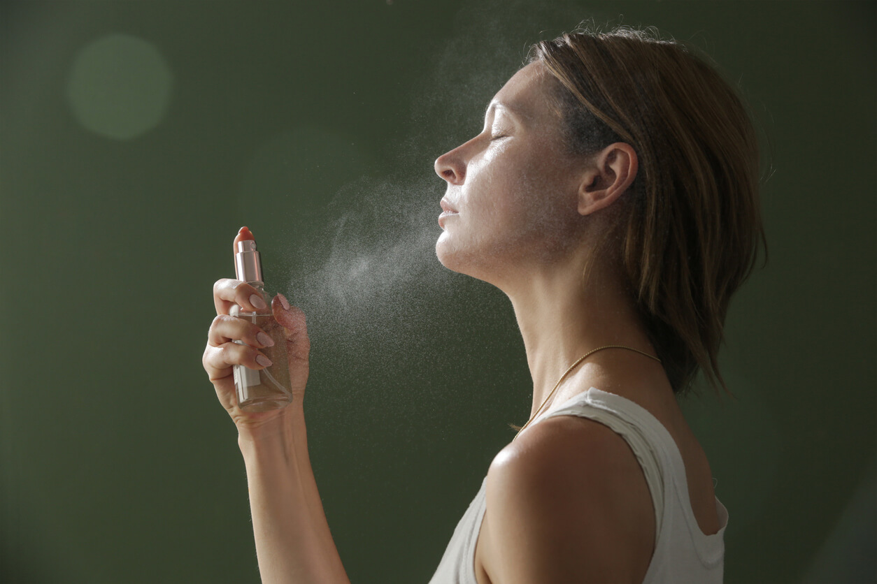kvinde sprayer setting spray i ansigtet oven på makeup