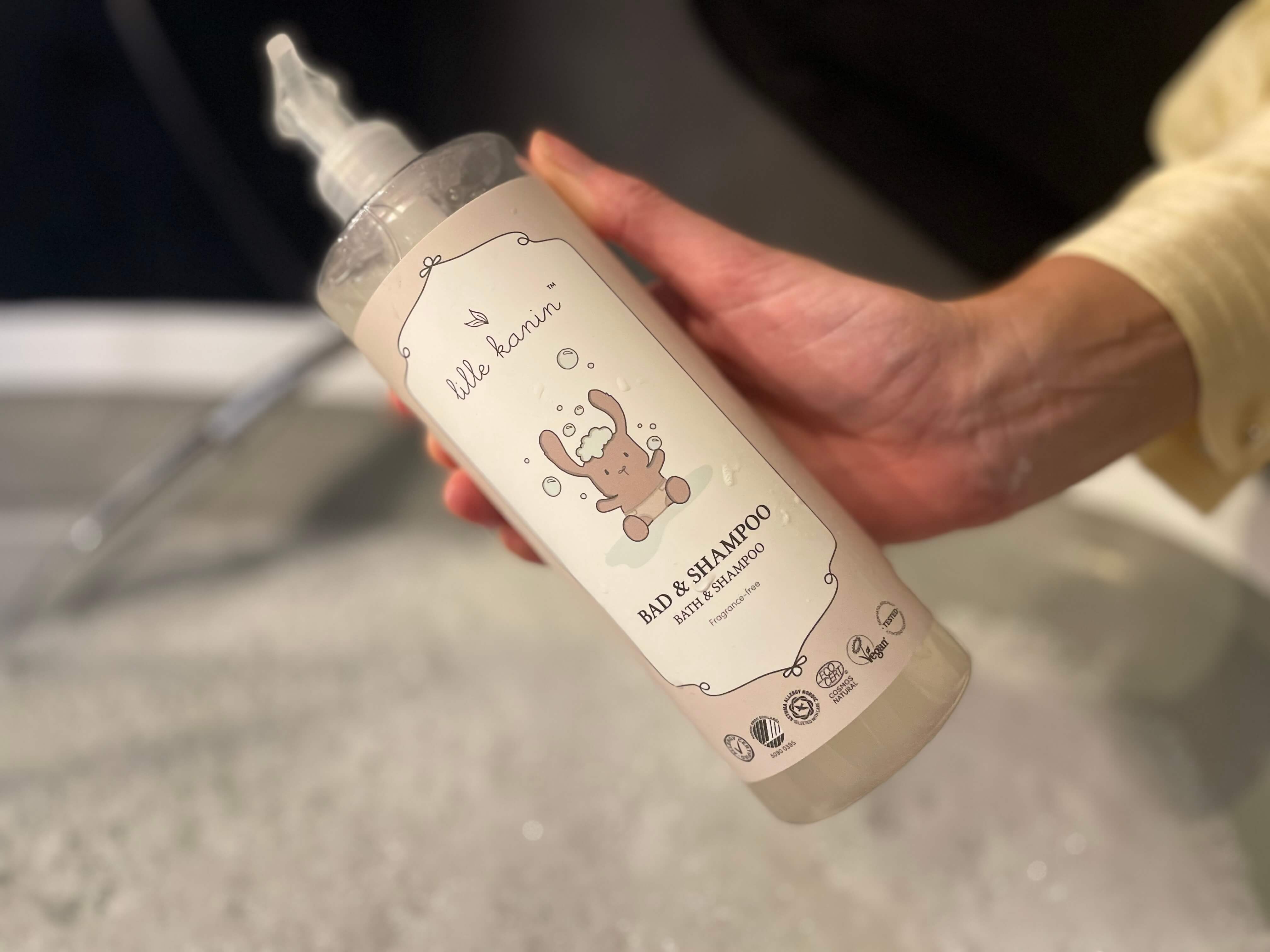 Lille Kanin Bad og shampoo i en hånd foran et badekar