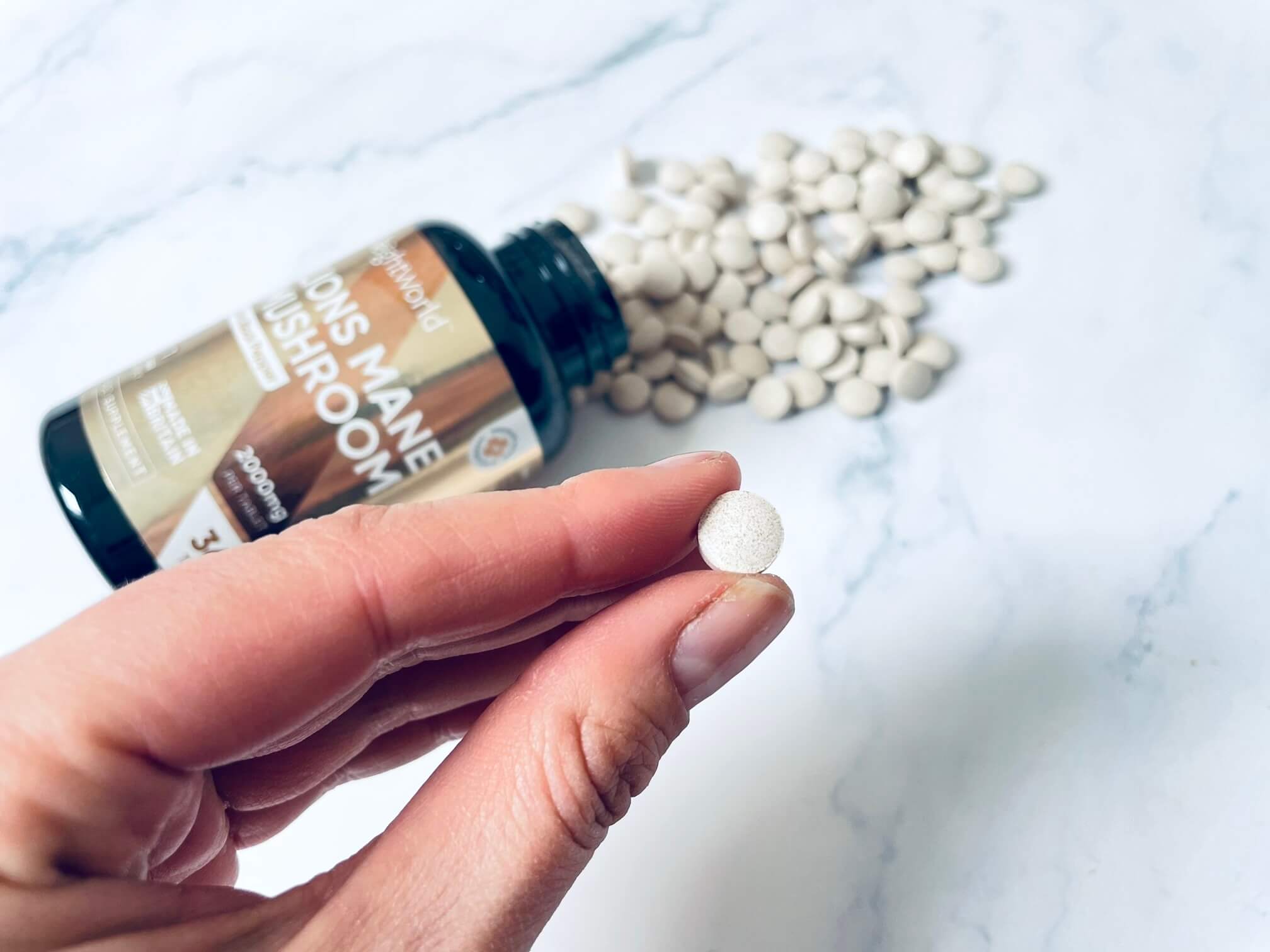 Lions Mane tablet mellem to fingre