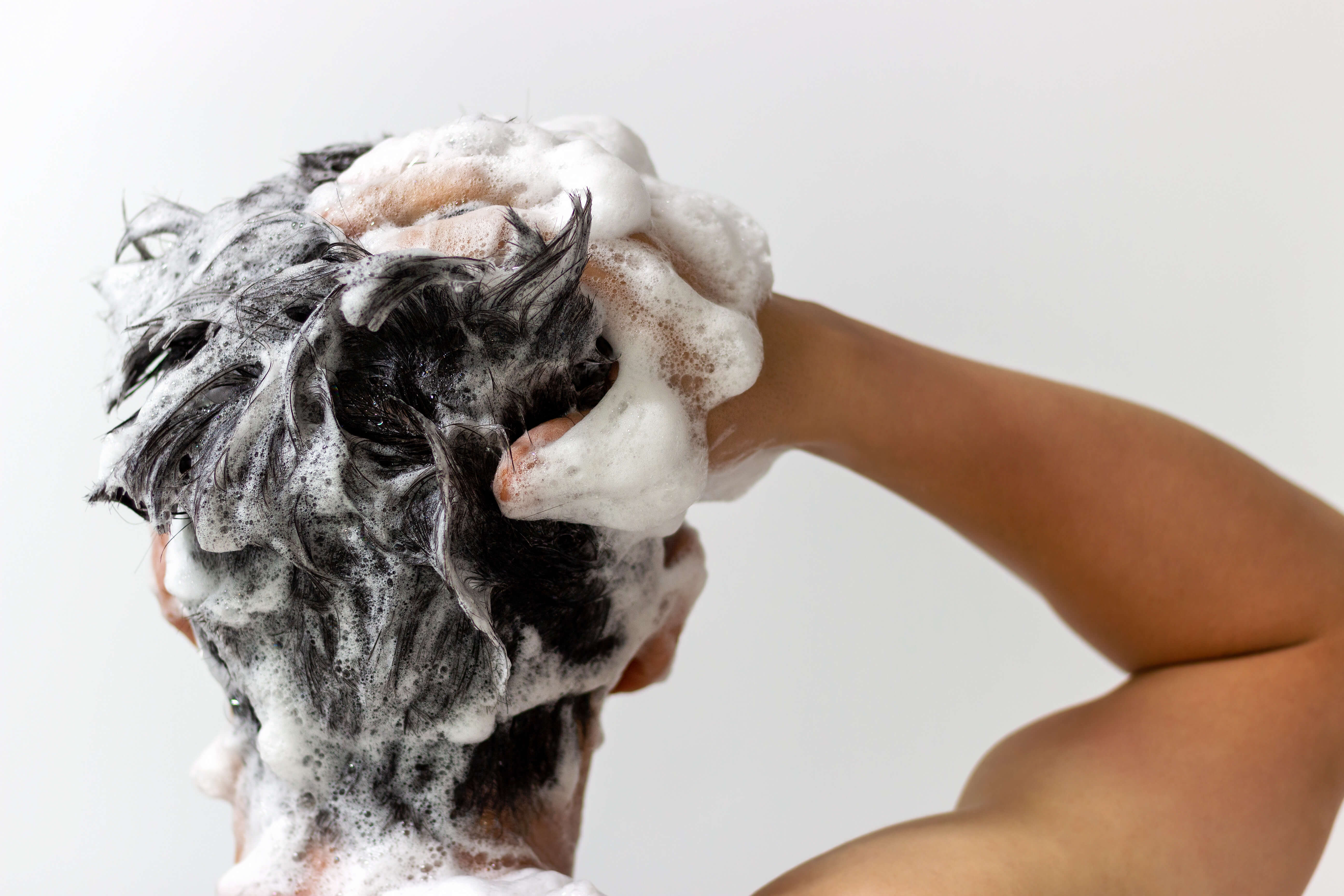 Mand med kort hår vasker hår med shampoo