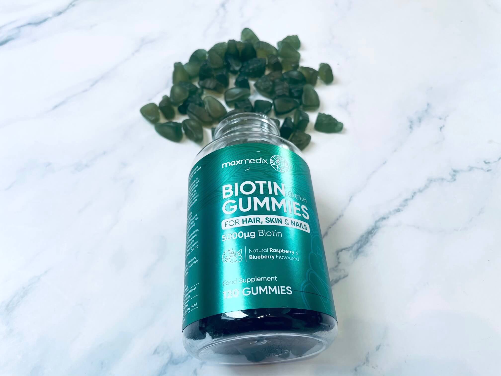 Maxmedix Biotin Gummies på bord med vitaminerne hældt ud