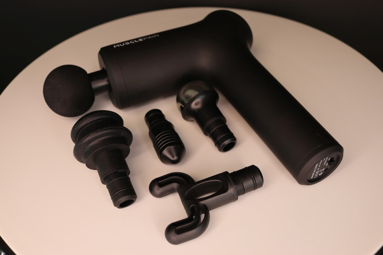 Musclepain massagepistol på bord med tilbehør