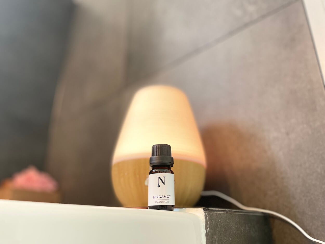 Naturligolie bergamotolie med en diffuser i baggrunden