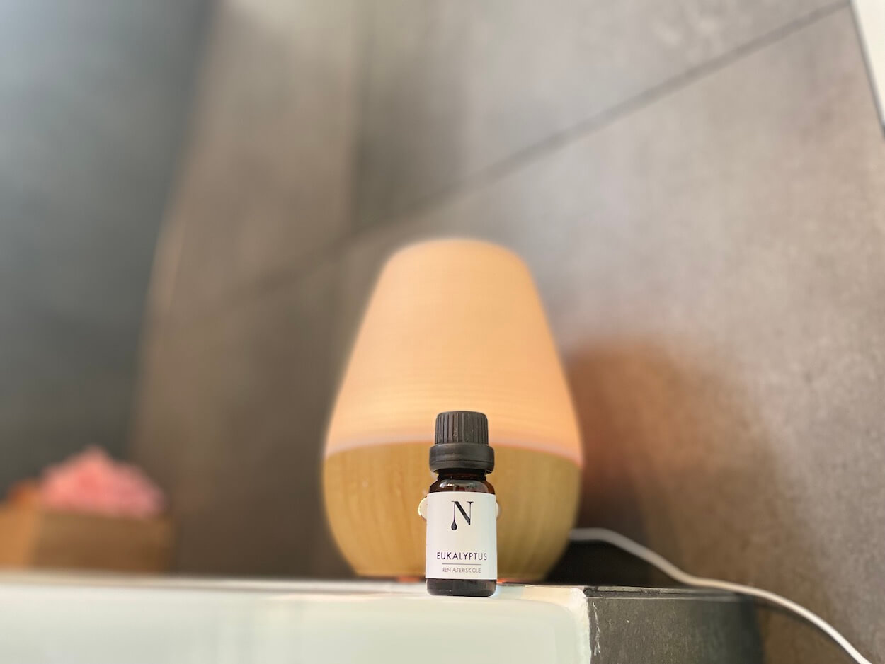 Naturligolie eukalyptusolie med diffuser i baggrunden