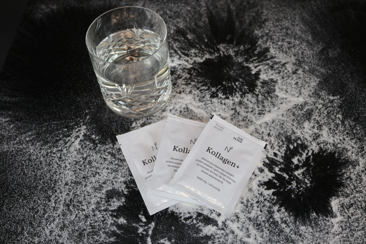 Nutrinic Kollagen Plus kollagenbreve på bord med glas vand