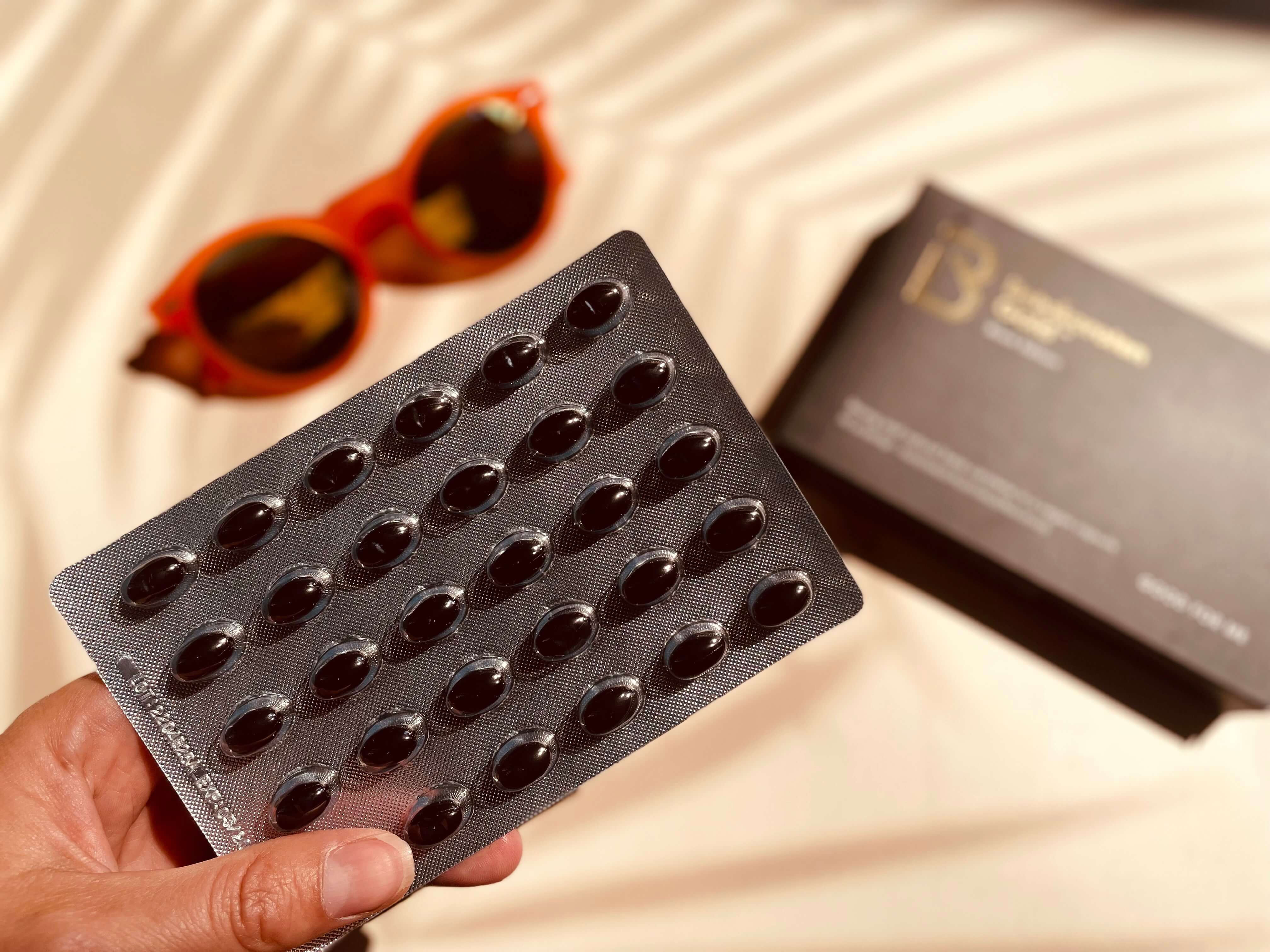 Pakke med Betakaroten Gold black edition i hånden på kvinde