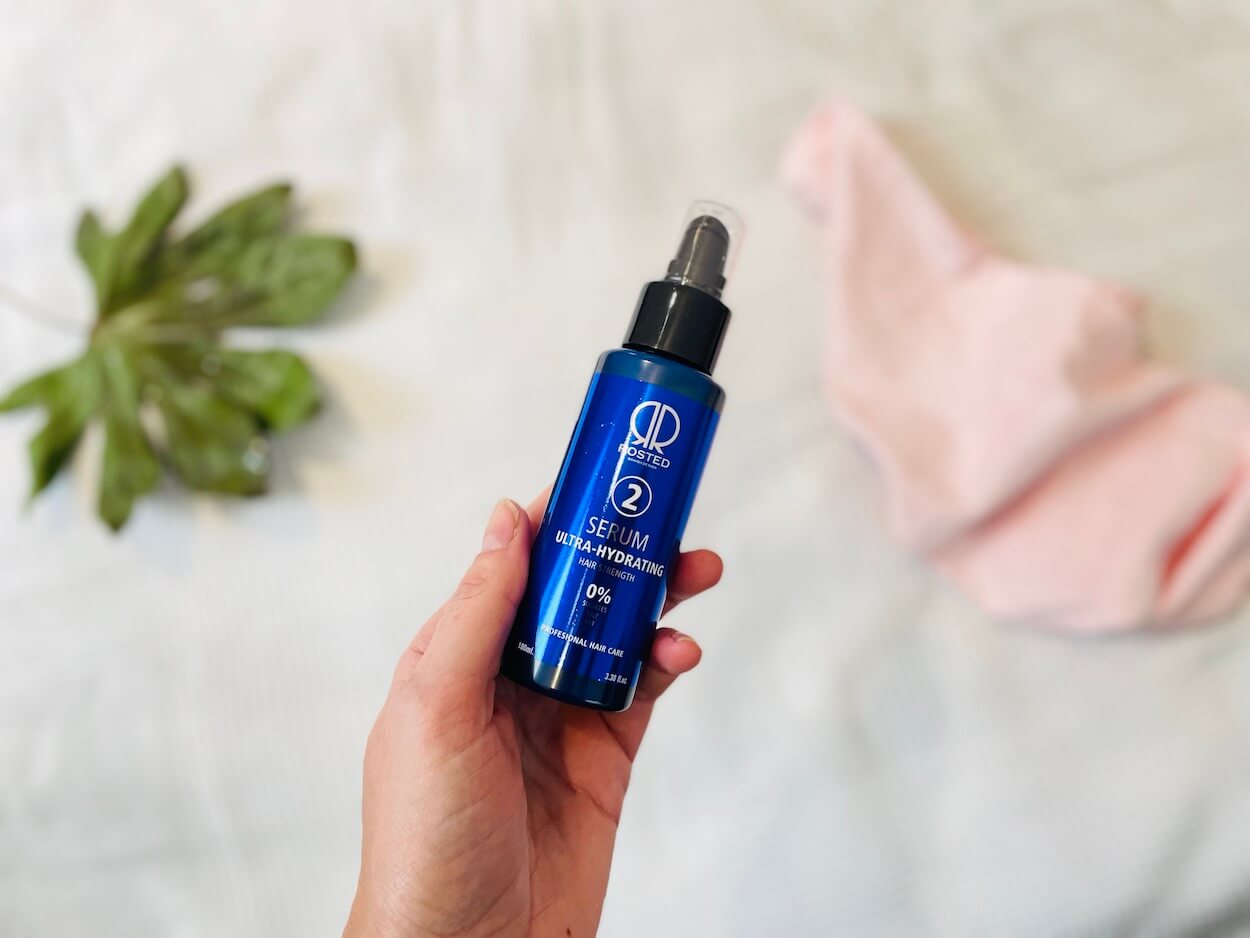  Rosted serum Argan olie i en hånd med seng i baggrunden