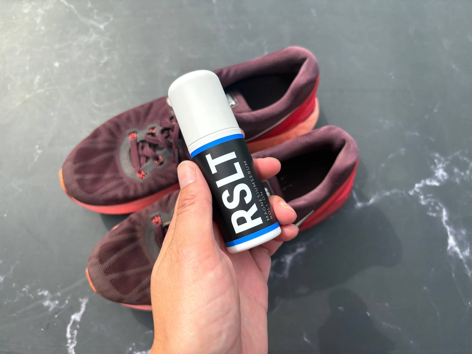 RSLT Magnesium Roll-On i hånd over træningssko