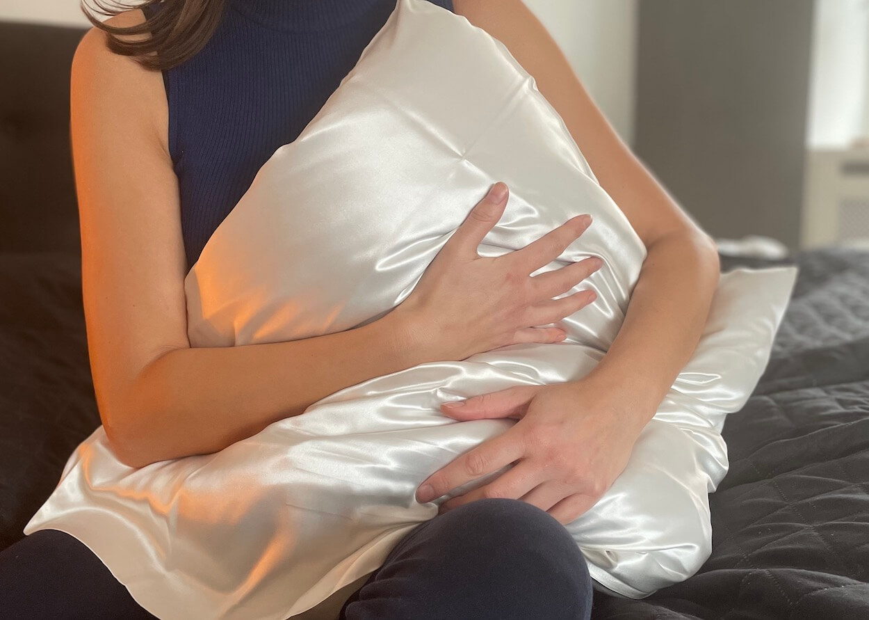 Silke pudebetræk fra Hugged på en pude der bliver krammet