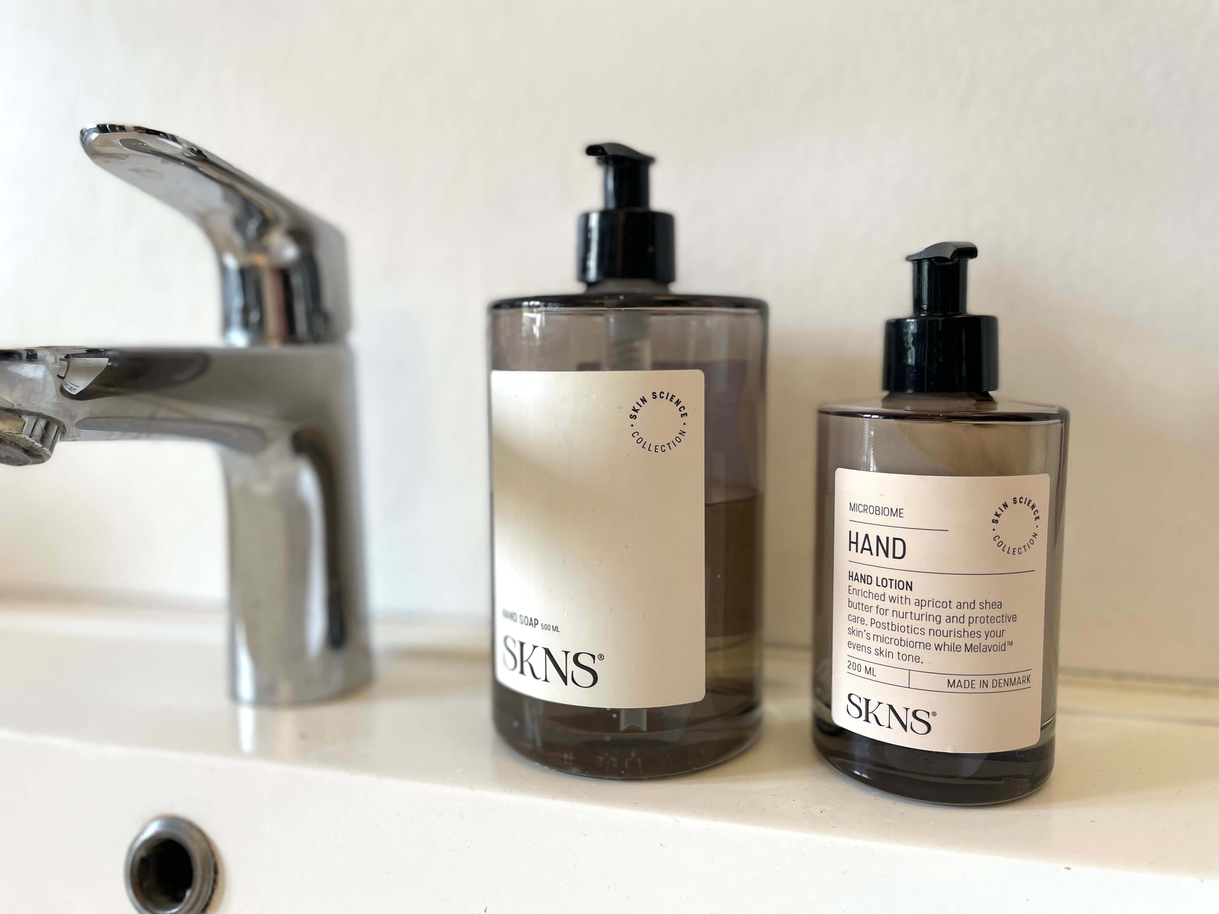 SKNS Hand Lotion ved side af SKNS håndsæbe på badeværelse