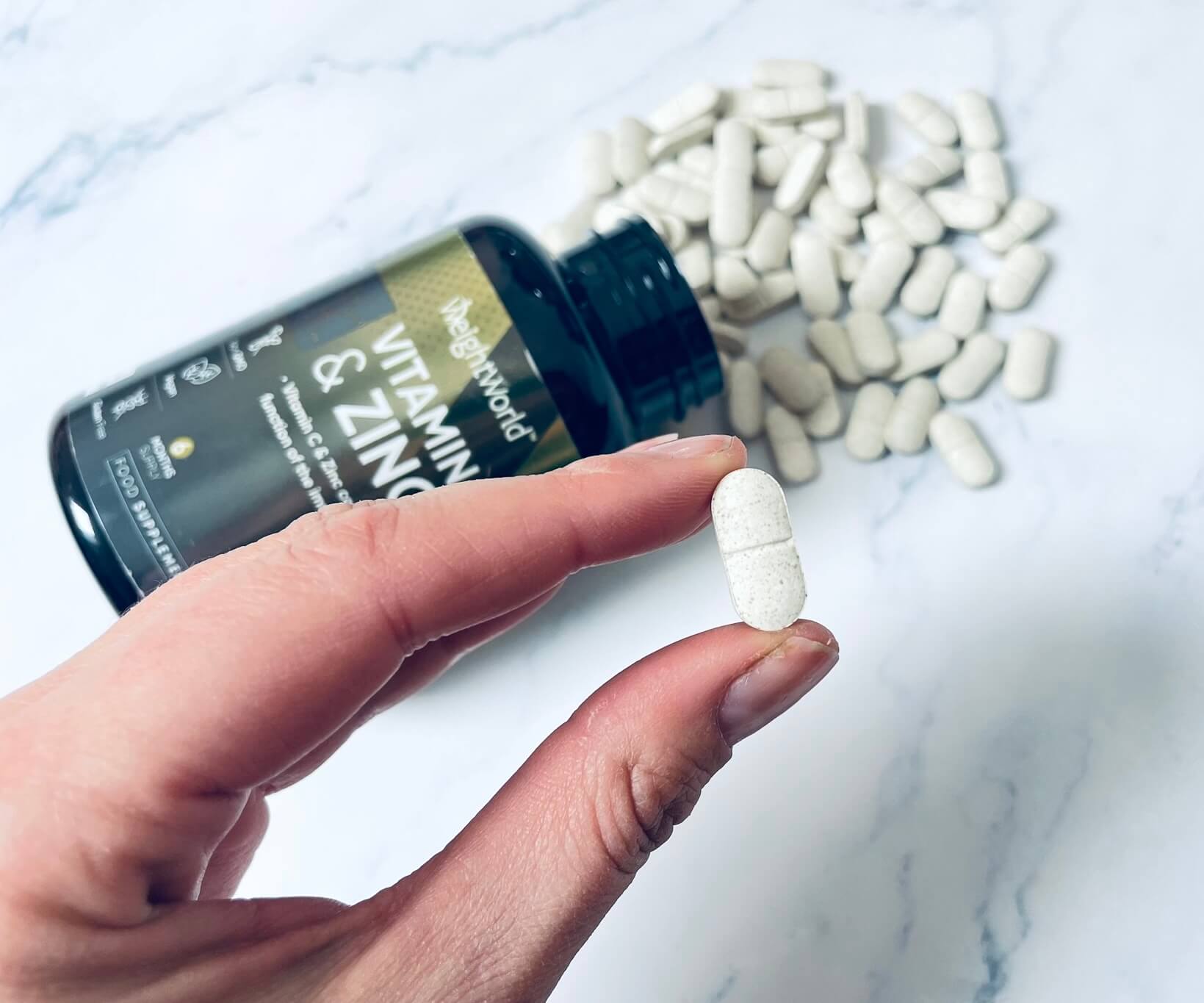 Tablet fra C-Vitamin + Zinktabletter fra Weightworld mellem to fingre