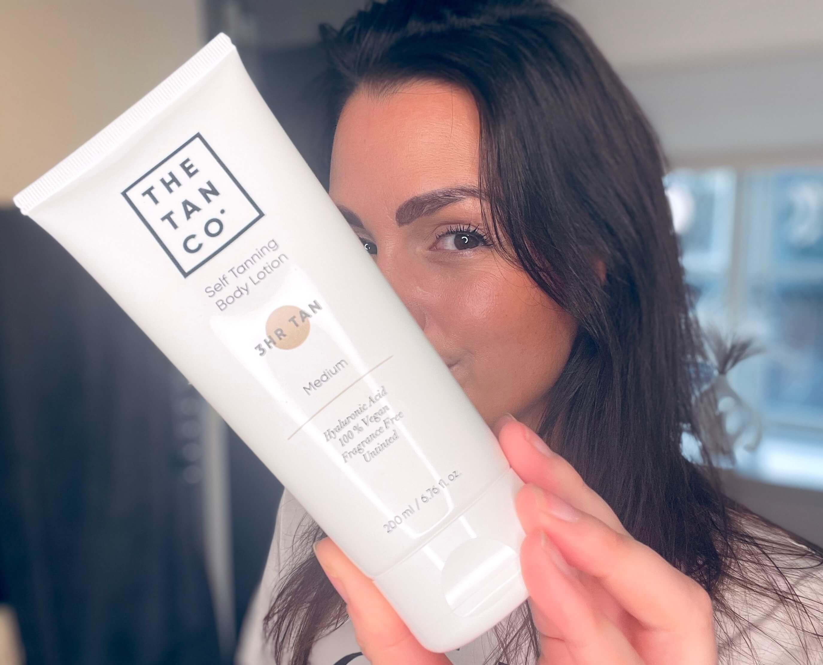 The Tan Co selvbruner lotion i hånd på kvinde