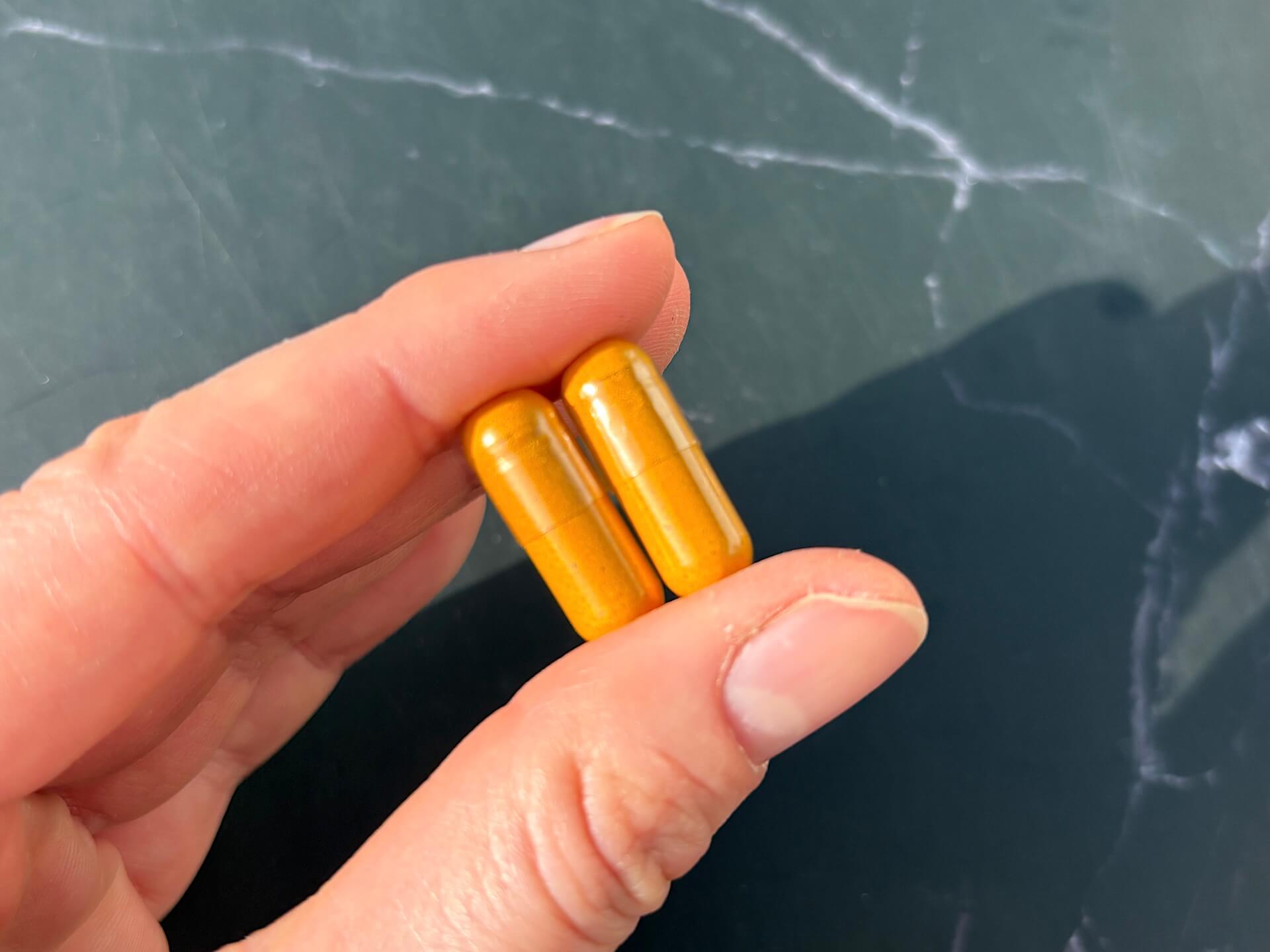 To WeightWorld Turmeric gurkemejekapsler mellem fingre