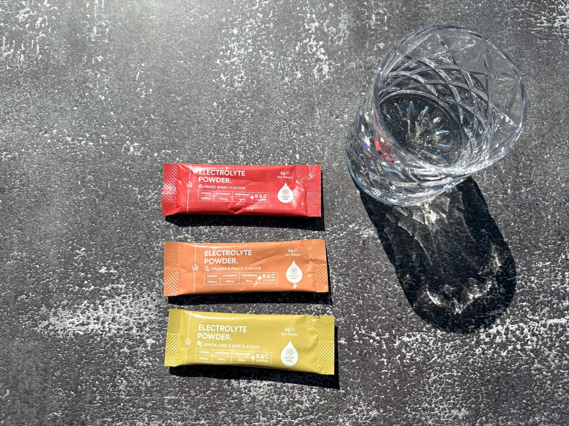 Tre pakker med Weightworld Electrolyte Powder ved siden af glas
