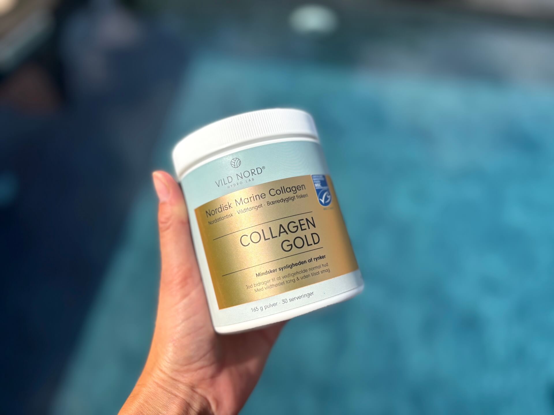 Vild Nord Collagen Gold i hånd over pool