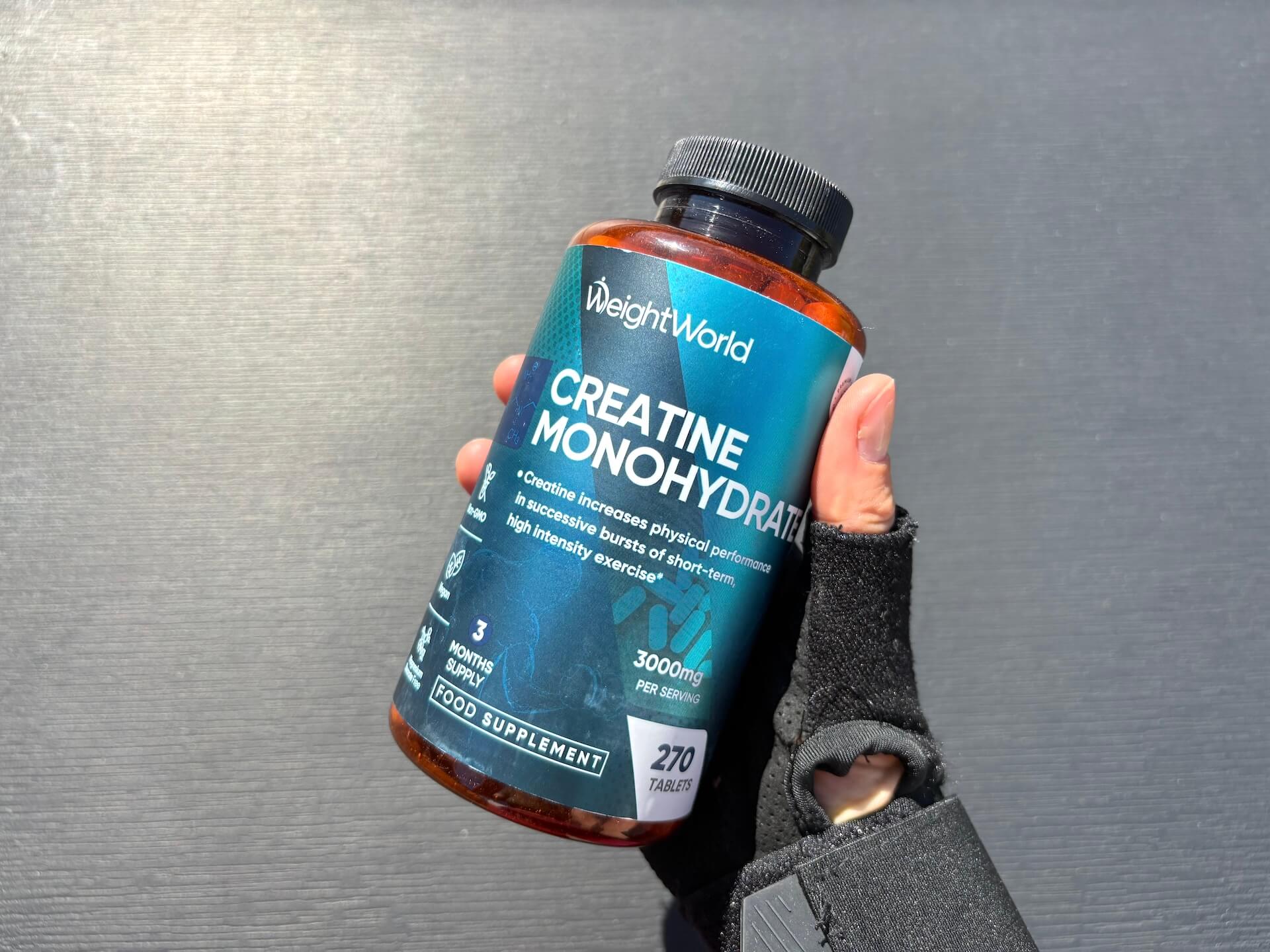 Weightworld Creatine Monohydrate tabletter i hånd med træningshandske