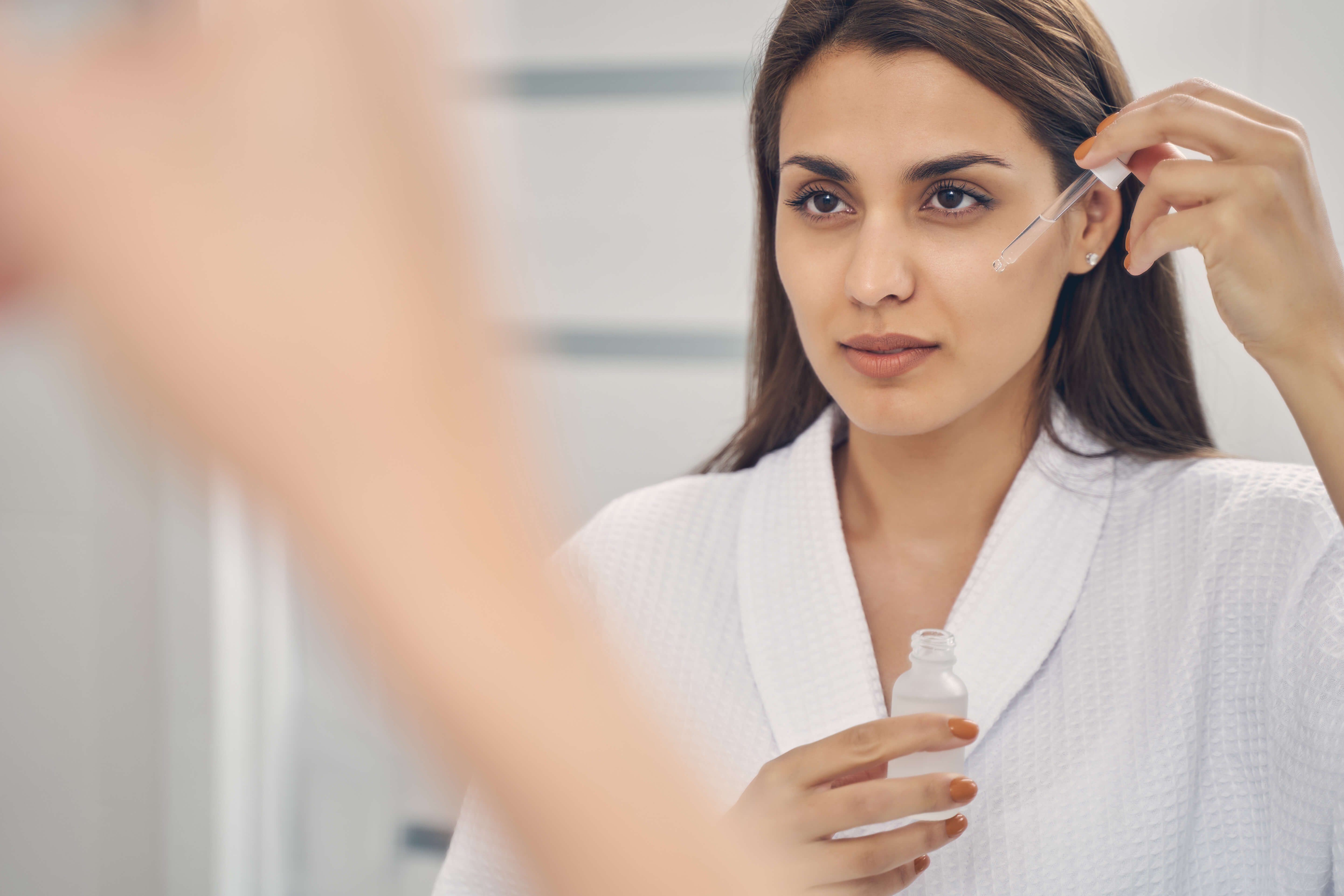Yngre kvinde bruger retinol serum i ansigtet