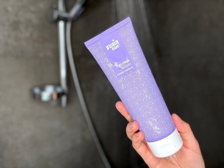 Yuaia Haircare Blond and Bright Conditioner i hånd i bruser