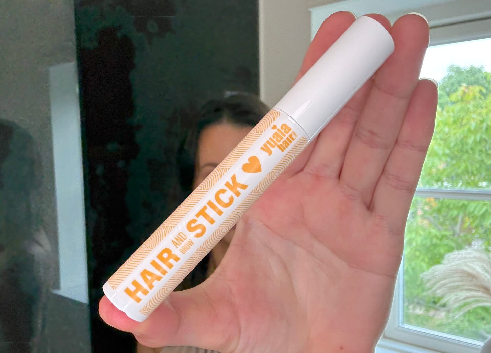 Yuaia Haircare Hair and Brow Stick i hånd på badeværelse