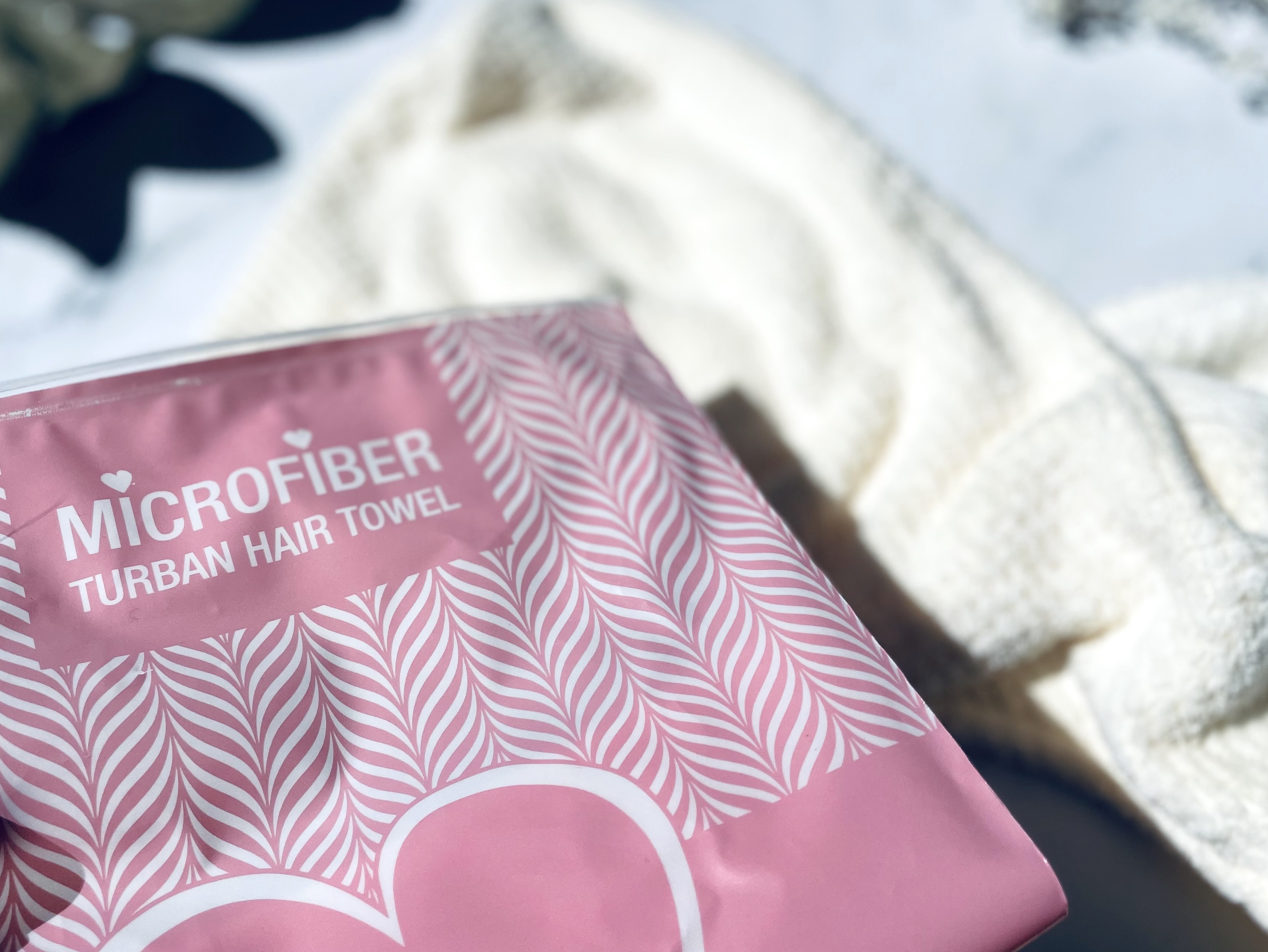 Yuaia Haircare Microfiber håndklæde til håret bagved den pose det kommer i
