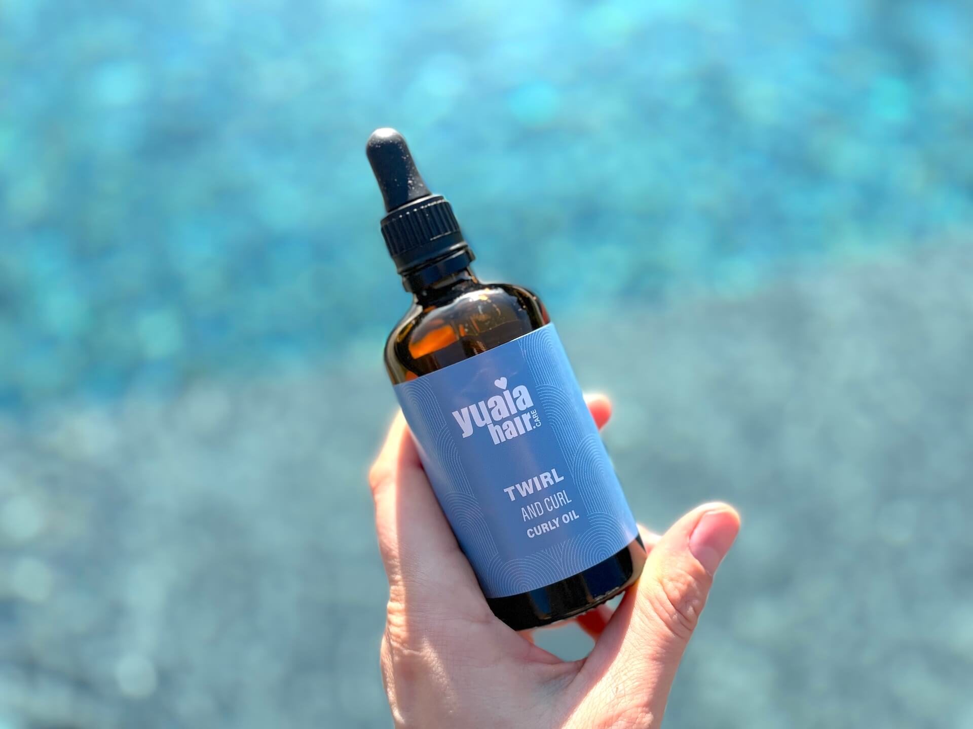 Yuaia Haircare Twirl and Curl Curly Oil flaske i hånd